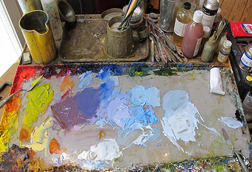 Dirty palette of the artist. Oil paints on a glass palette. Stock Photo